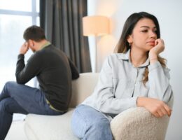 Beautiful couple is sitting back to back on the couch while having a quarrel