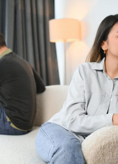 Beautiful couple is sitting back to back on the couch while having a quarrel