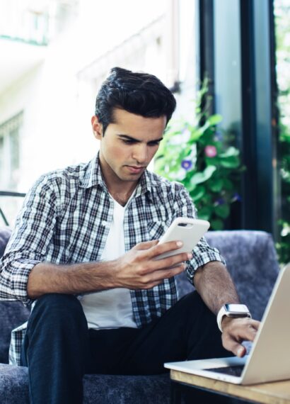 Caucaisan male blogger checking received email while sending sms message on mobile phone