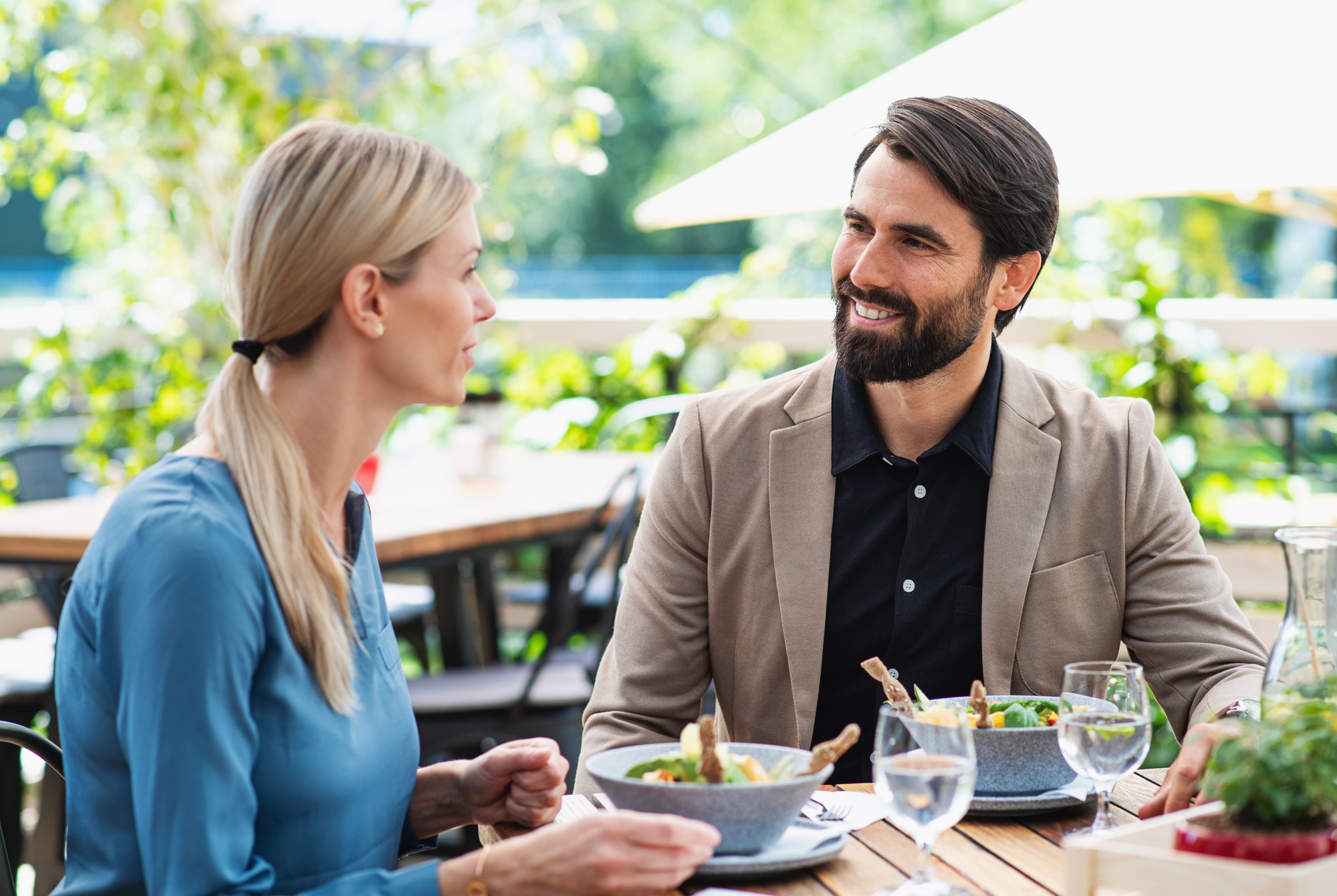 Happy couple sitting outdoors on terrace restaurant, talking