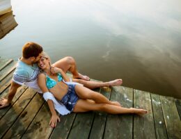Loving couple sitting on the pier on lake