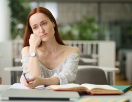 Sad woman sitting at table with books