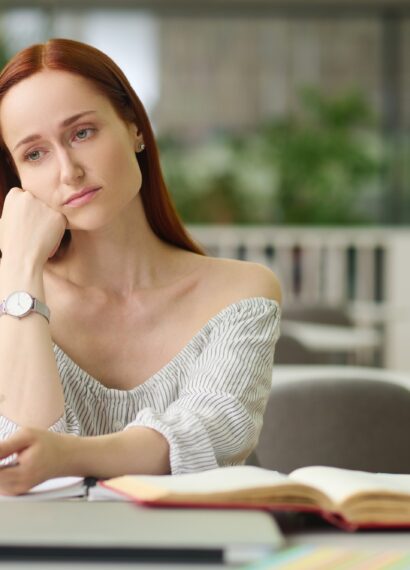 Sad woman sitting at table with books