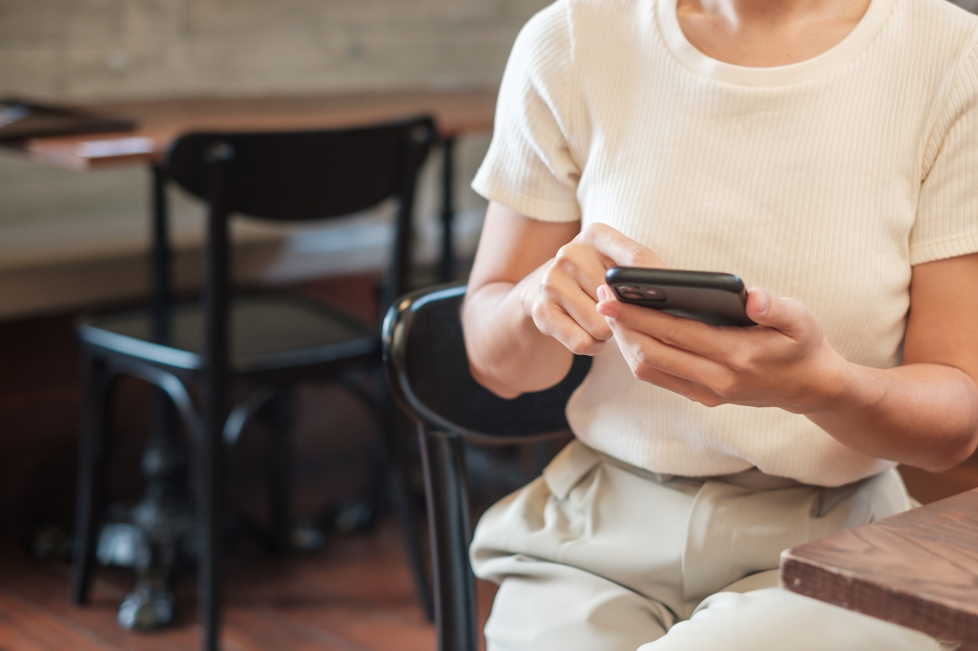 woman holding and using smartphone for sms messages, young woman typing touchscreen mobile phone