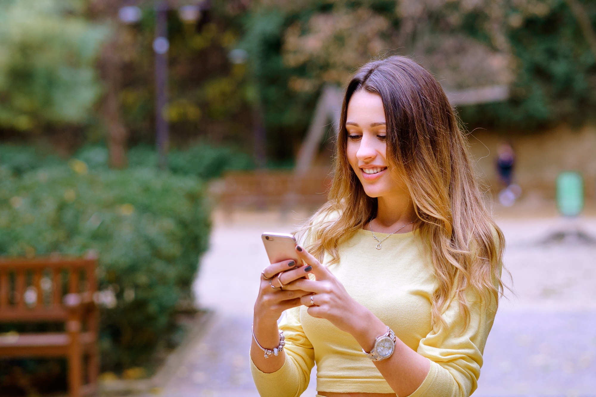 Young female with a cellphone sending a happy message isolated on a blurred background