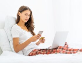 Young woman shopping online, entering code from SMS message on mobile phone, security